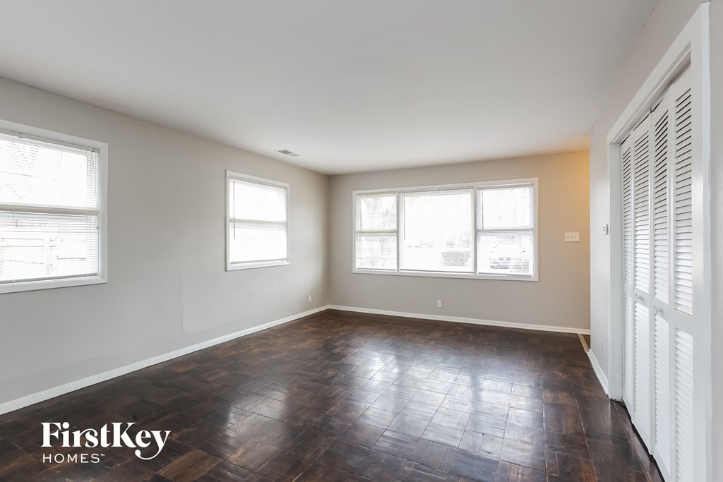 an empty living room with wood floors and three windows
