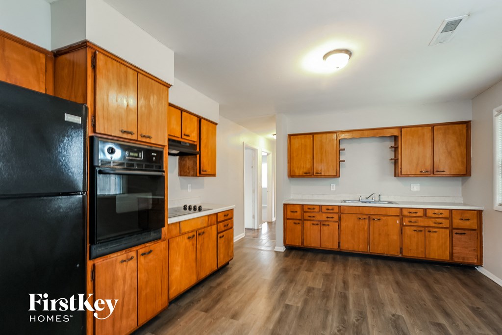 a kitchen with wooden cabinets and a black refrigerator