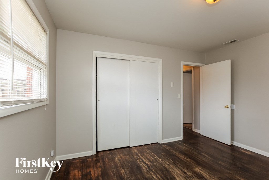 a bedroom with a door to a closet and a window