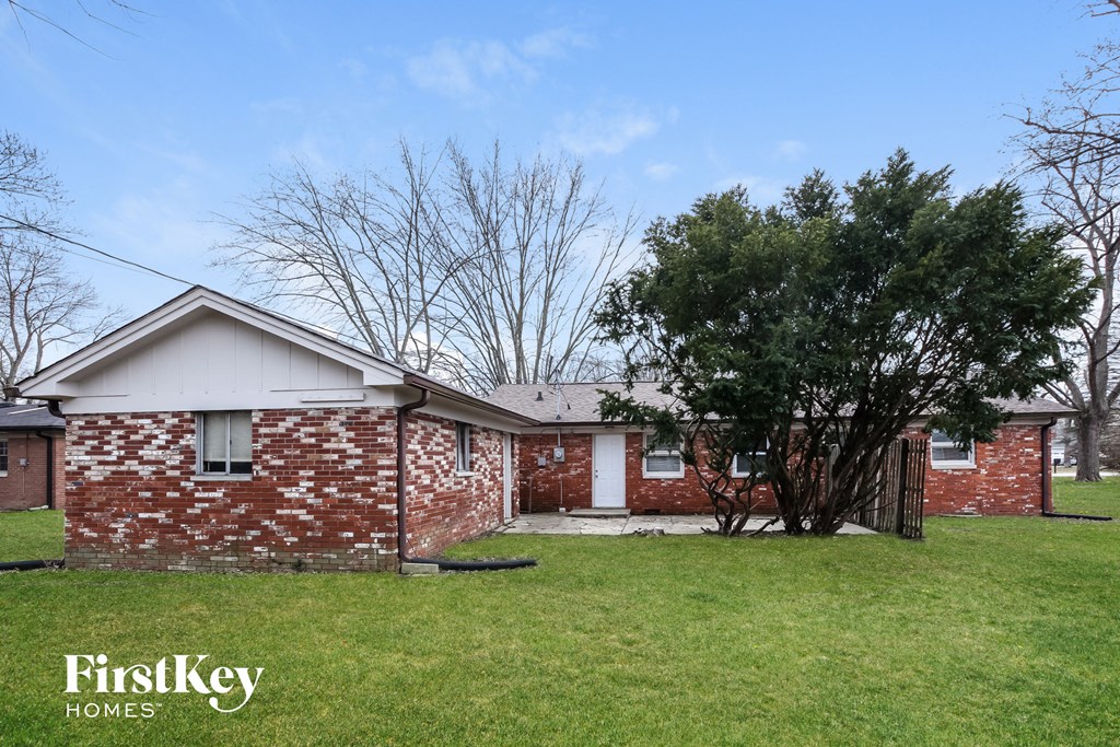 a brick house with a grassy yard and a tree
