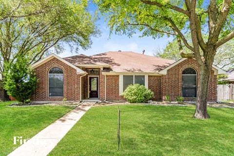 a small brick house with a lawn and trees