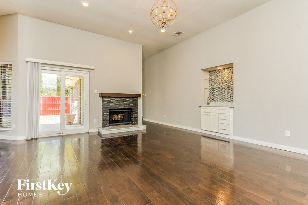 an empty living room with a fireplace and wooden floors
