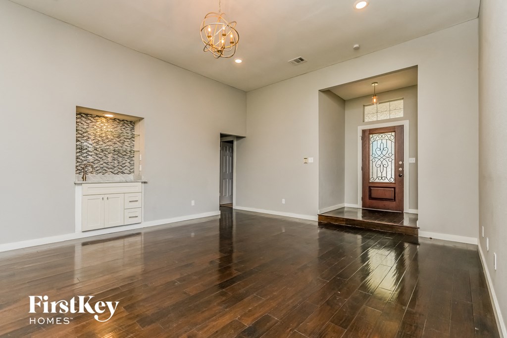 an empty living room with white walls and wood floors and a wooden door
