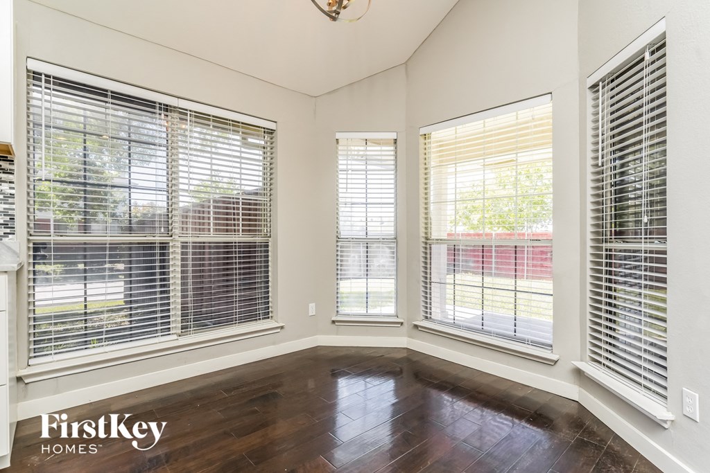 an empty living room with three windows and wood floors