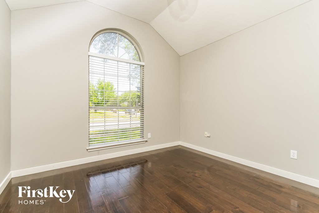 the living room of an empty house with a large window and wooden floors