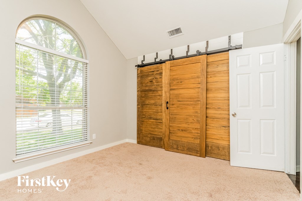 a bedroom with a large window and a closet with wooden doors