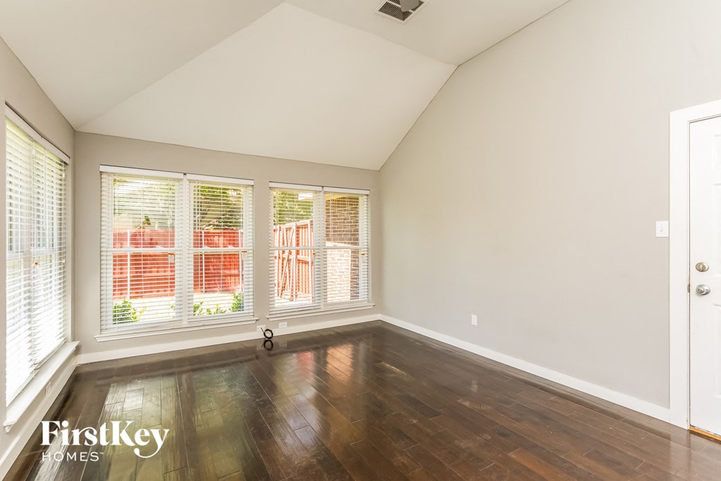 an empty living room with wood floors and a large window