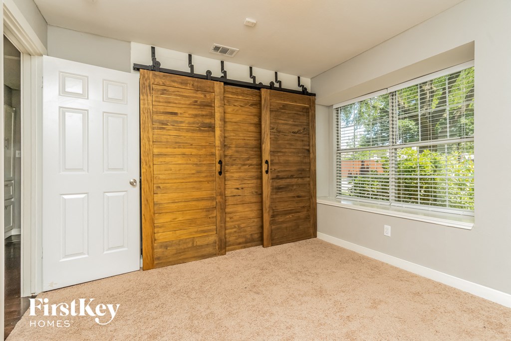 a bedroom with a large window and a closet with wooden doors