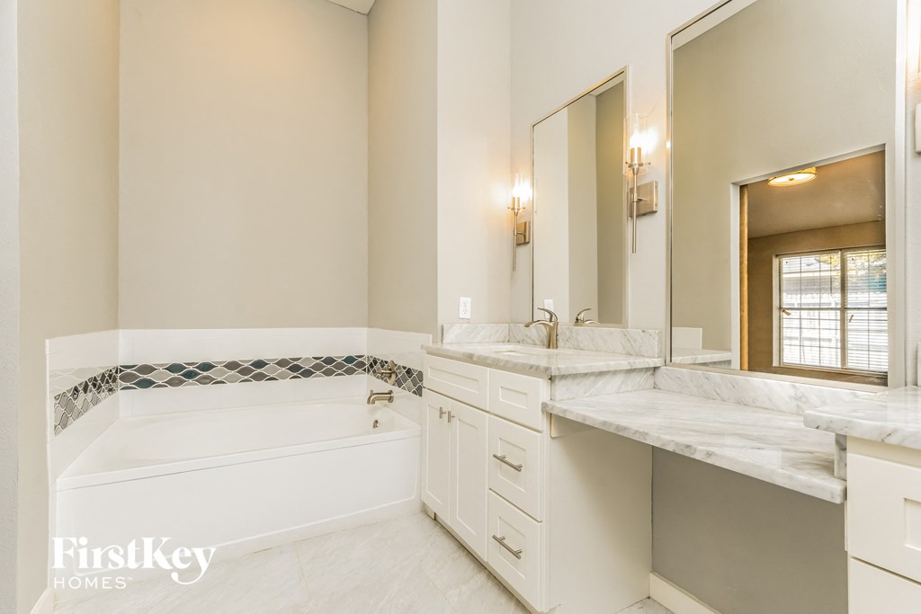 a white bathroom with a tub and two sinks
