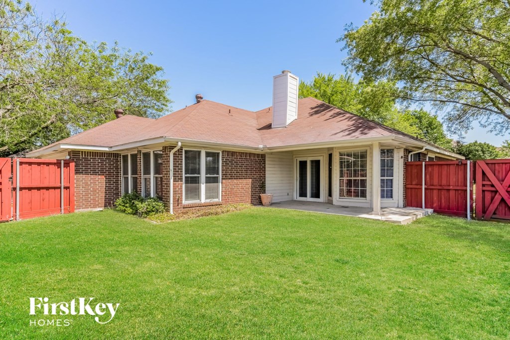 a small brick house with a yard and a red fence