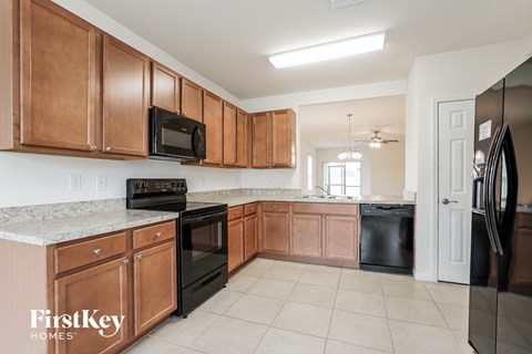 A kitchen with brown cabinets and black appliances.