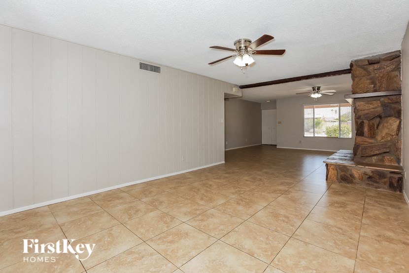 a large living room with a fireplace and a ceiling fan