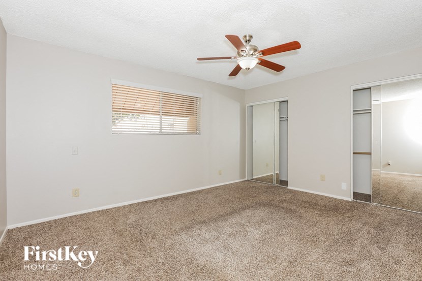 a spacious living room with carpet and a ceiling fan