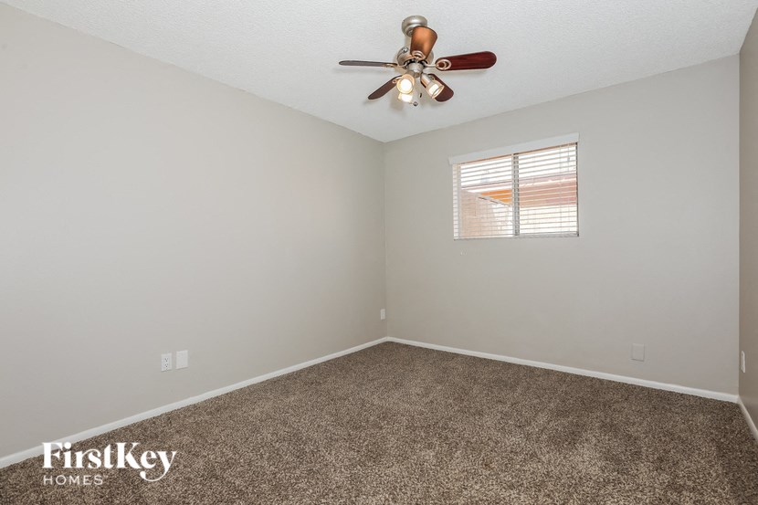 the bedroom has a ceiling fan and a carpet
