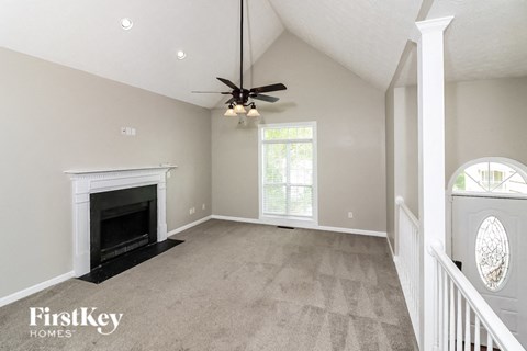 an empty living room with a fireplace and a ceiling fan