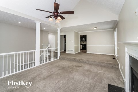 a empty living room with a ceiling fan and stairs