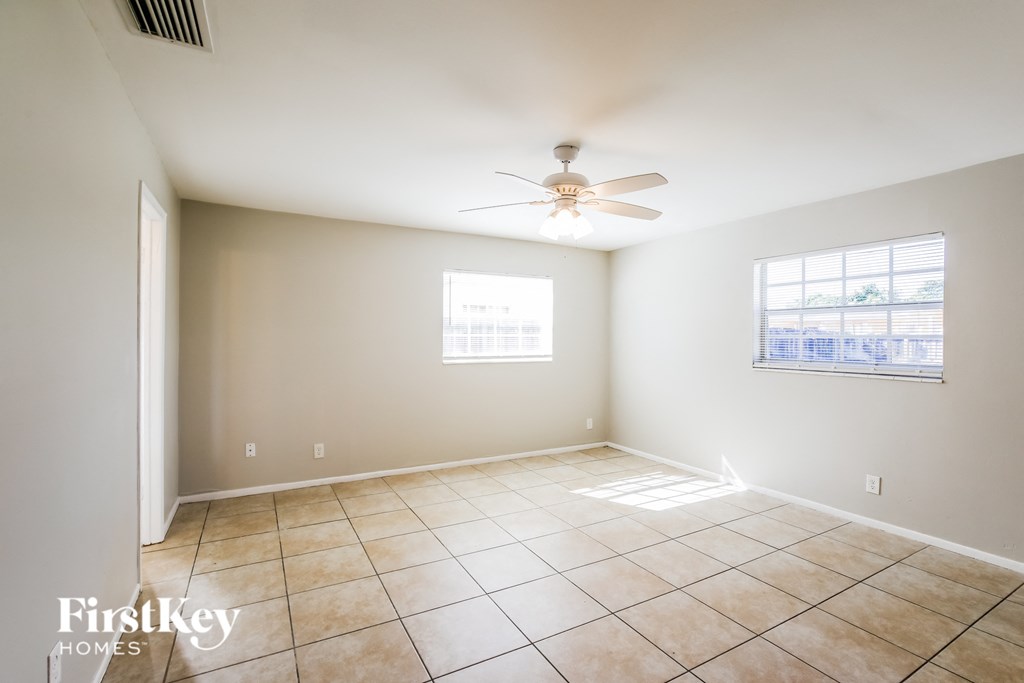 a empty living room with a ceiling fan and tiled floors