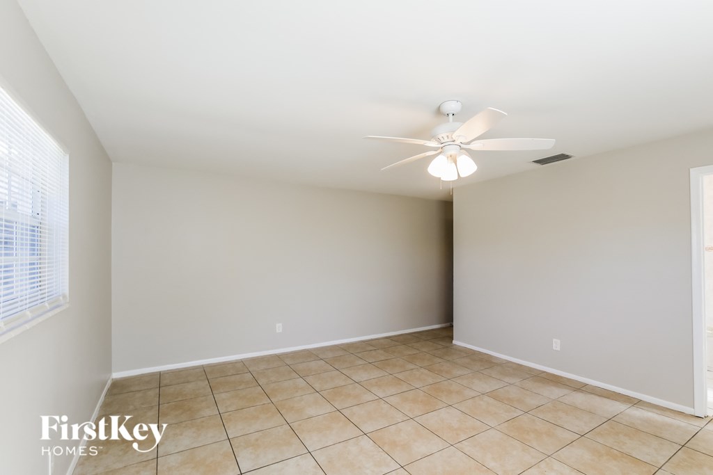 a empty living room with a ceiling fan and tiled floors