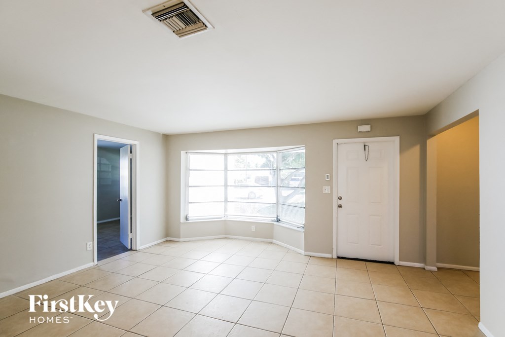 an empty living room with a white door and a window