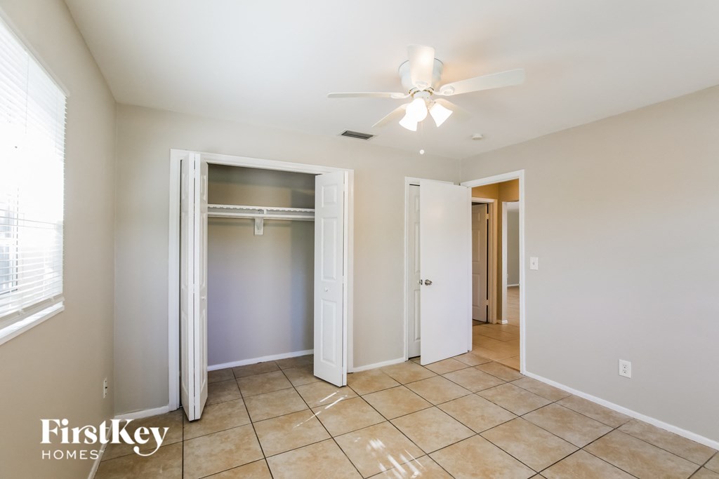 a bedroom with a ceiling fan and a closet