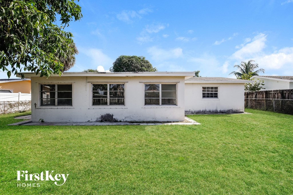 a small white house with a grassy yard and a fence