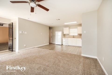 A spacious living room with a carpeted floor and a ceiling fan.