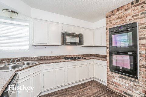 a kitchen with white cabinets and a brick wall