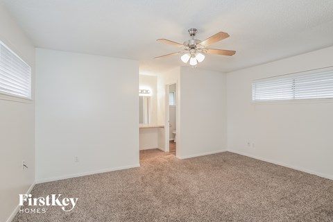 a spacious living room with carpet and a ceiling fan