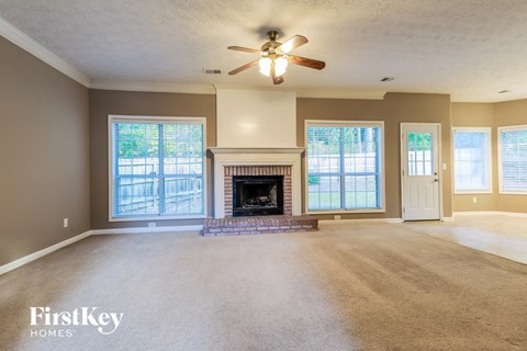 an empty living room with a fireplace and a ceiling fan