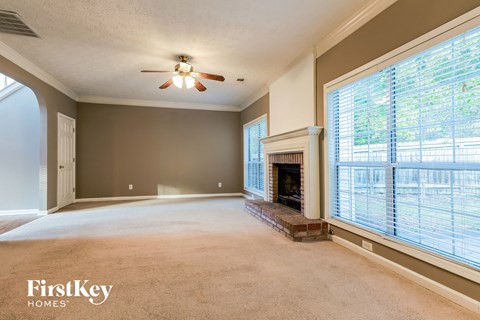 an empty living room with a fireplace and a ceiling fan