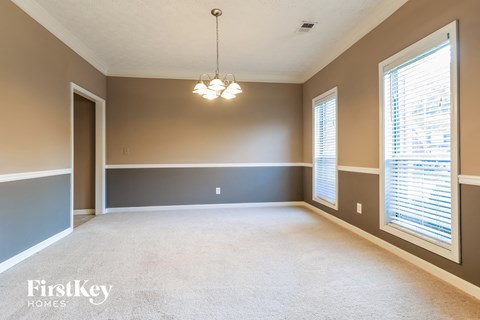 an empty living room with two windows and a chandelier