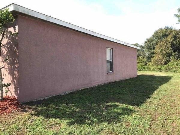 A small pink building with a window and a metal roof.