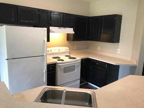 A kitchen with black cabinets and a white refrigerator.