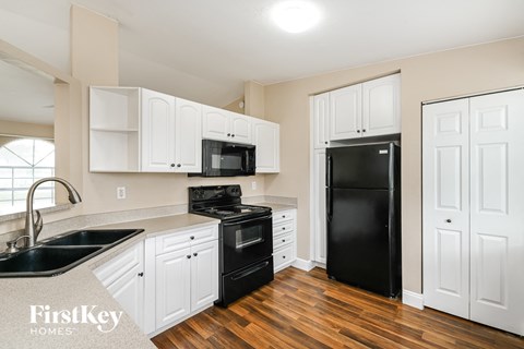 a kitchen with white cabinets and black appliances