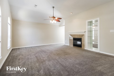 A spacious living room with a fireplace and a ceiling fan.