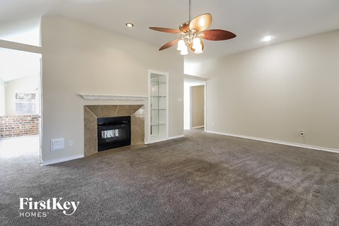 A spacious living room with a fireplace and a ceiling fan.