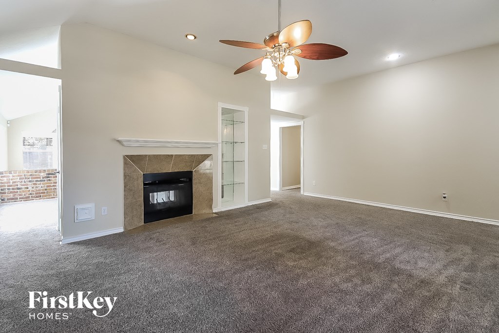A spacious living room with a fireplace and a ceiling fan.