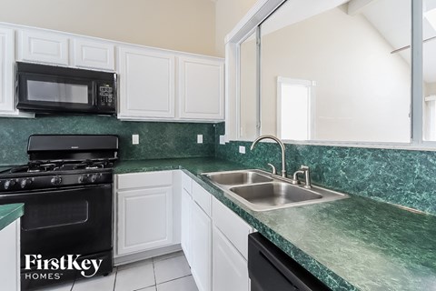 A kitchen with a black stove top oven and a green counter top.