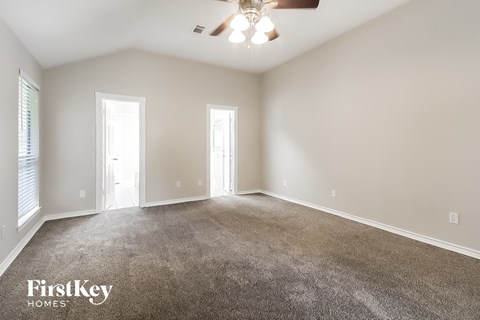 A spacious room with a carpeted floor and a ceiling fan.