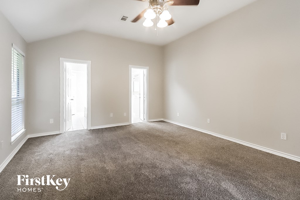 A spacious room with a carpeted floor and a ceiling fan.