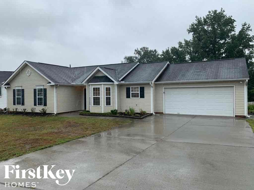 A house with a wet driveway and a FirstKey Homes logo.
