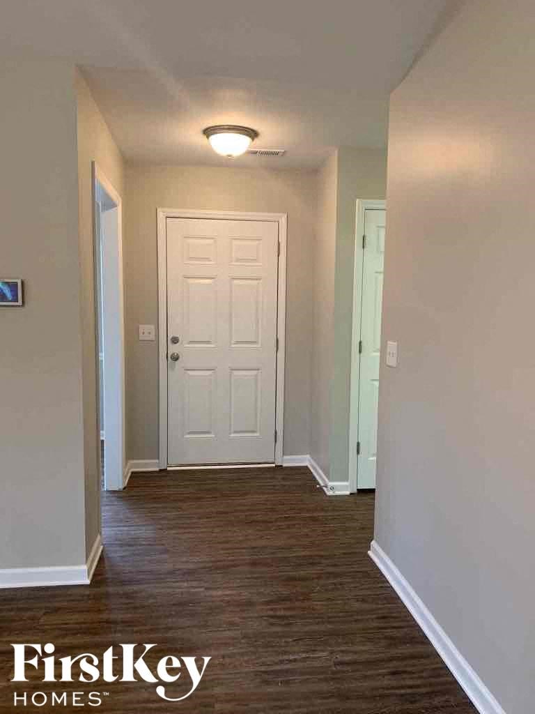 A hallway with a white door and wooden floors.