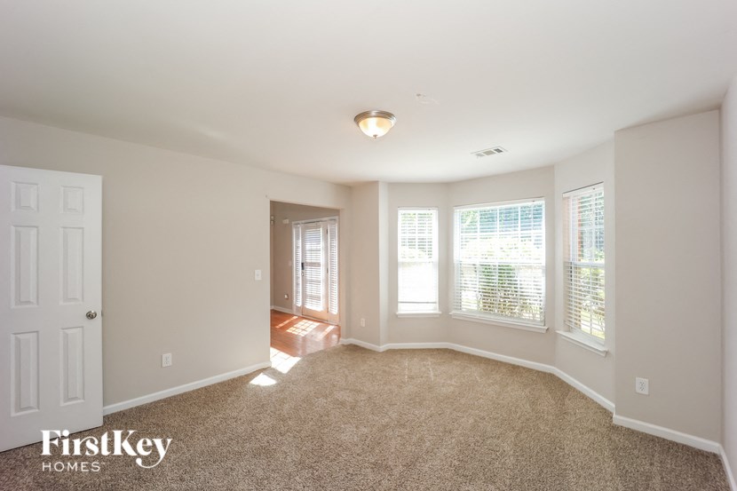 an empty living room with three windows and a white door