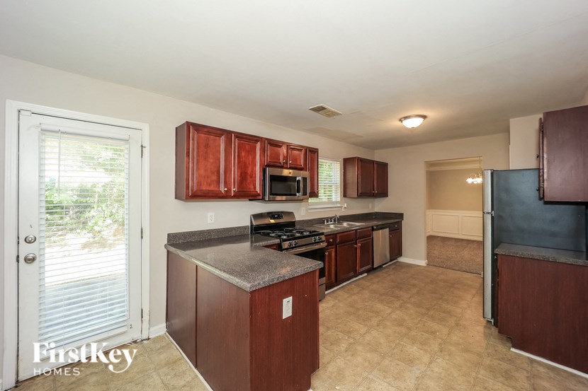a kitchen with wood cabinets and black appliances and a sliding glass door