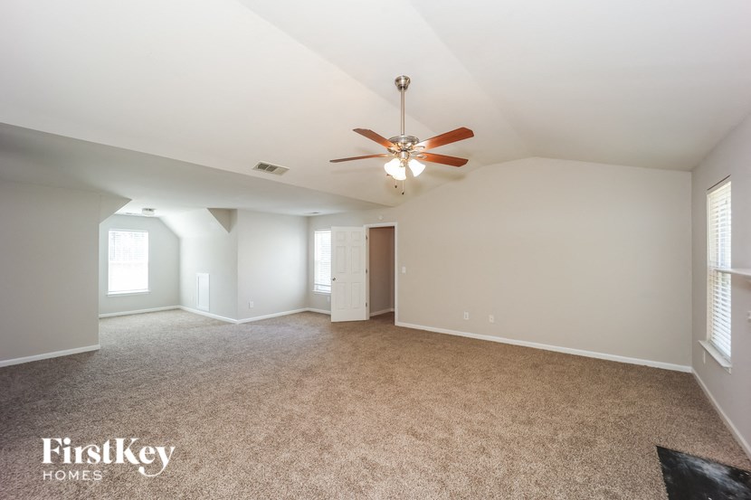 a living room with carpet and a ceiling fan