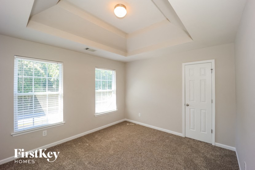 an empty room with a white door and two windows