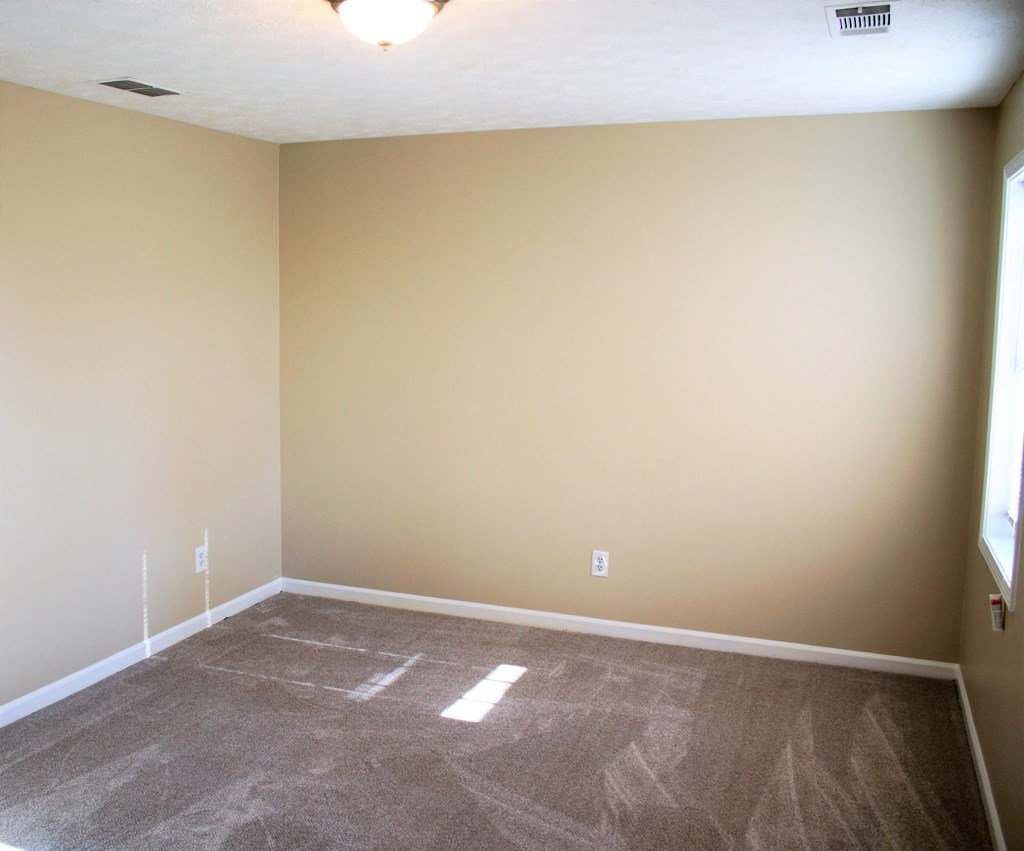 A room with a carpeted floor and a window on the right side.