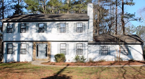 A white house with a brown roof and a chimney.