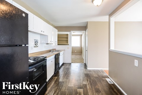 a kitchen with white cabinets and black appliances and wood floors