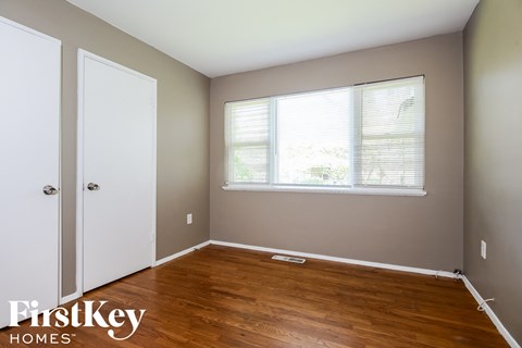 a bedroom with wood floors and a window and a closet